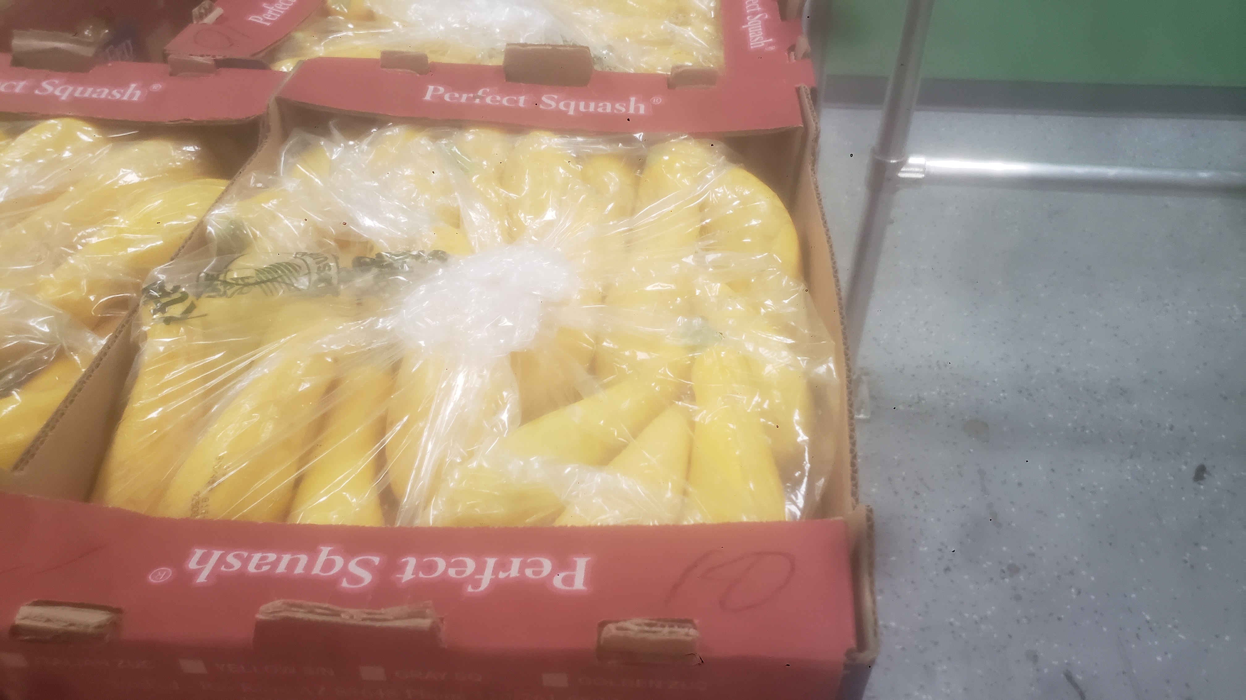 Summer squashes covered in plastic and placed in a tray.